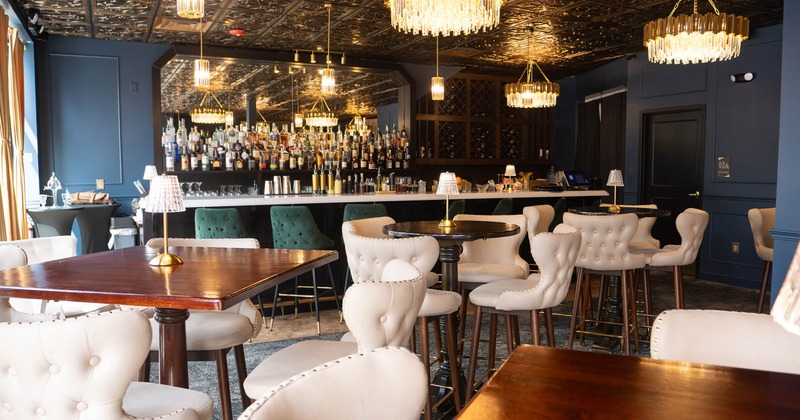 Interior, high seating area, wooden top tables with padded stools, bar in the back