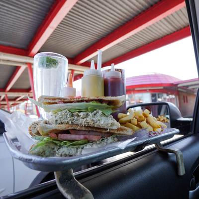 tuna salad sandwich french fries and a limeade on tray hanging on car window.