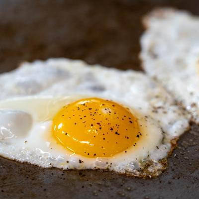 Fried egg cooking on hot griddle.
