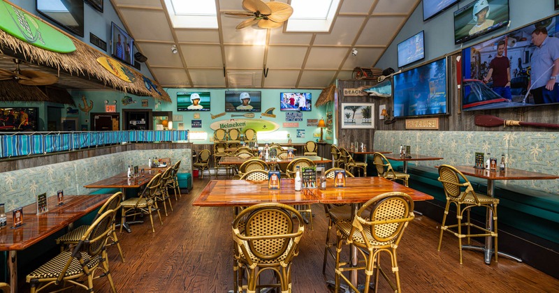 Inside, dining area with wooden tables and chairs, TVs on the walls