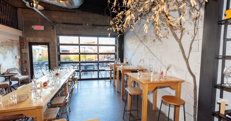 Interior with wooden tables and chairs, large window and decorative plant