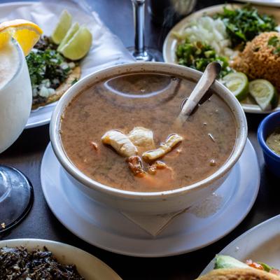 Bowl of seafood soup served on the tavle alongside other menu items.