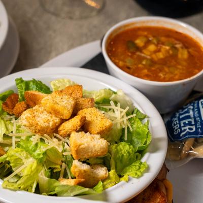 Caesar salad served alongside bowl of chili with crackers on the side.