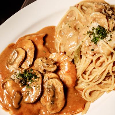 Veal Marsala served with a side of Pasta Carbonara, close-up.