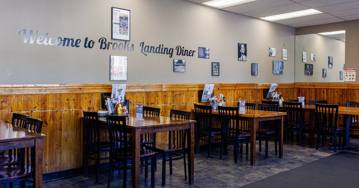Cozy diner interior with wooden tables and chairs lined against a paneled wall