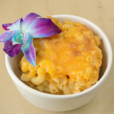 Mac and cheese bowl garnished with a purple flower.