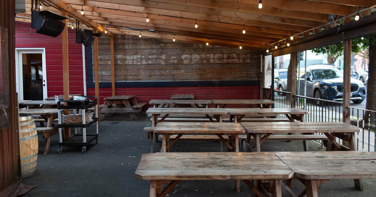 Exterior, covered seating area, wooden tables with benches, ceiling lanterns, carpet flooring