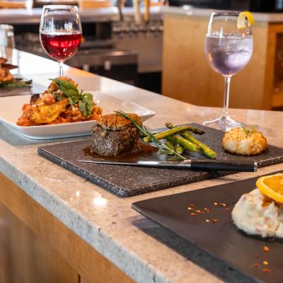 Filet and Crab Cake and Parmesan Crusted Chicken on a counter served with drinks.