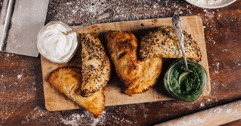 Hand pies served with cilantro dipping sauce and creamy sauce