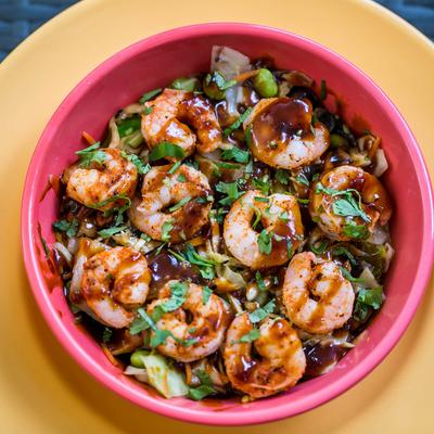 Shrimp dish with veggies, topped with sauce and cilantro.