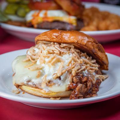 Pulled pork sandwich, topped with melted cheese and fried onions.