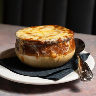Onion Soup Au Gratin served in a crock with spoon on the side.