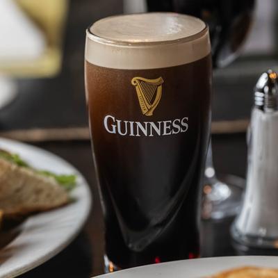 A pint of dark Irish beer with a creamy head on a table.