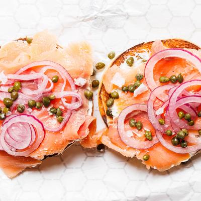 Smoked salmon bagel topped with cream cheese, red onion rings, and capers.