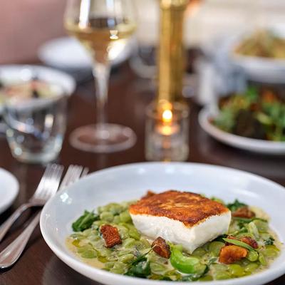 Grilled fish filet served over a creamy fava bean and vegetable ragout.
