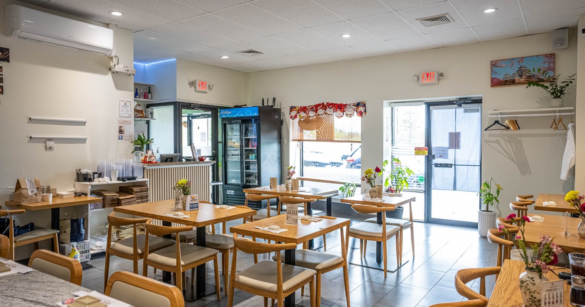 Interior of a bright, modern restaurant with wooden tables, chairs, drinks refrigerator