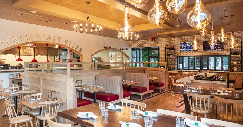 Restaurant interior, dining area with set dining tables, open kitchen and bar