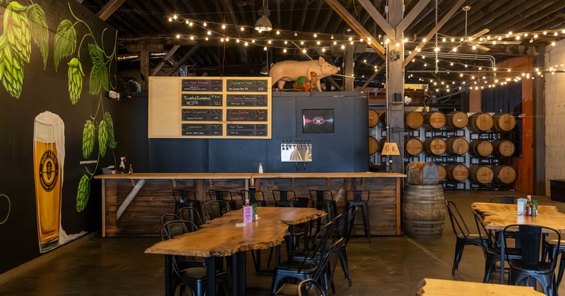 Taproom with exposed wooden beams, string lights and a long communal table