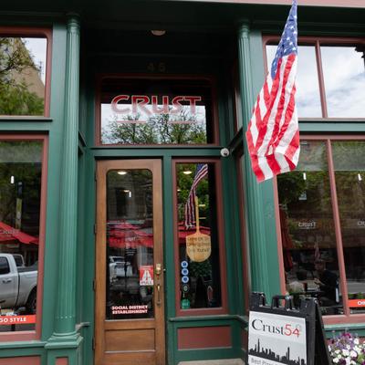 Crust 54 restaurant entrance with signage and an American flag.
