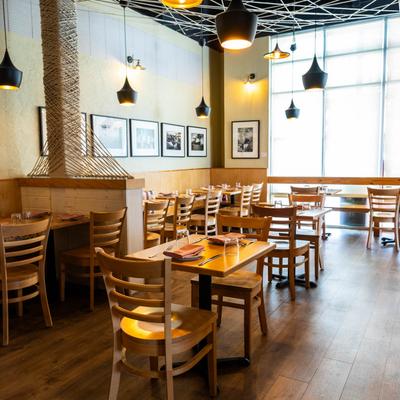 Sunlit dining room with wooden tables, chairs, and modern pendant lights.