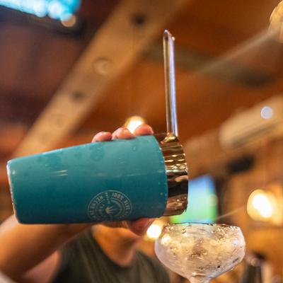 Bartender straining cocktail into a coupette glass.