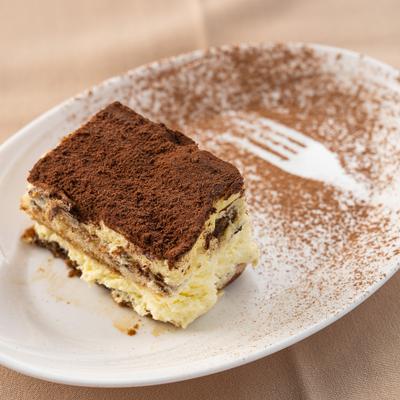 Tiramisu served on a plate with an additional fork-shaped dusting of cocoa.