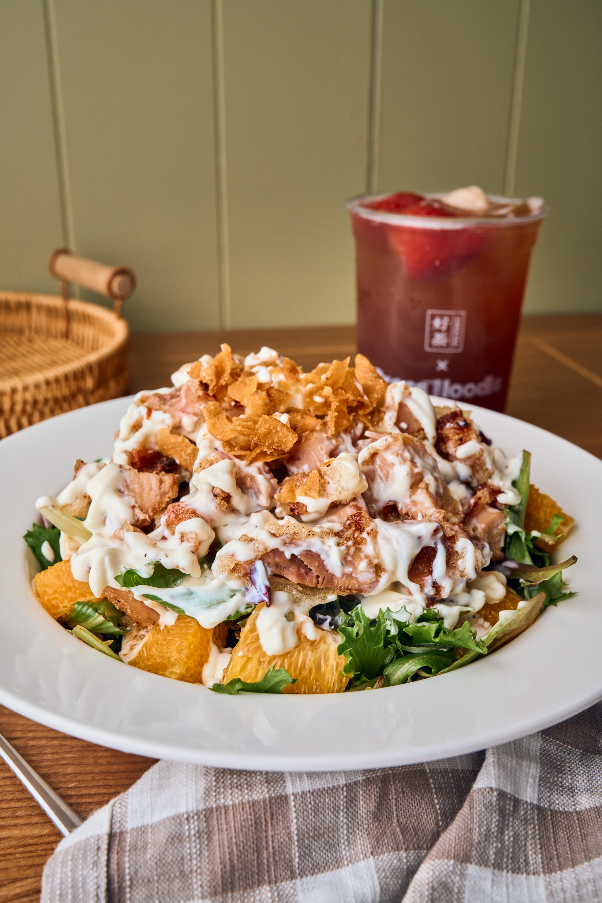 Orange Chicken Salad bowl and a cup of strawberry fruit tea on a wooden table
