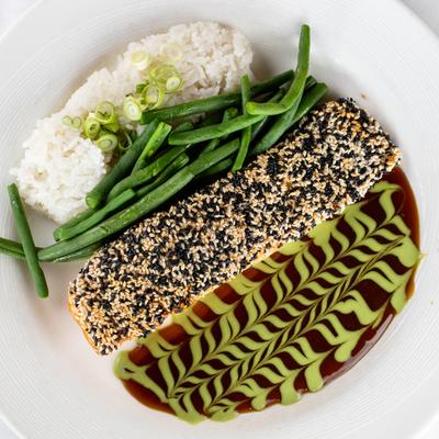 Sesame Crusted Salmon served with rice, green beans, and sauces on the side.