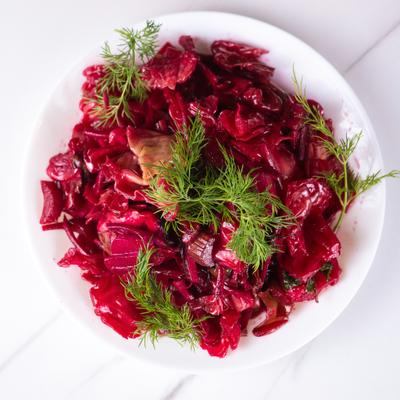 Marinated red cabbage on a white plate, garnished with fresh dill.