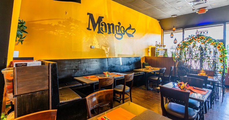Interior with yellow walls and tables set with orange placemats and floral arrangements.
