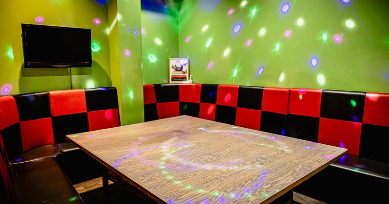 A large booth with a wooden table surrounded by upholstered seating and disco lights