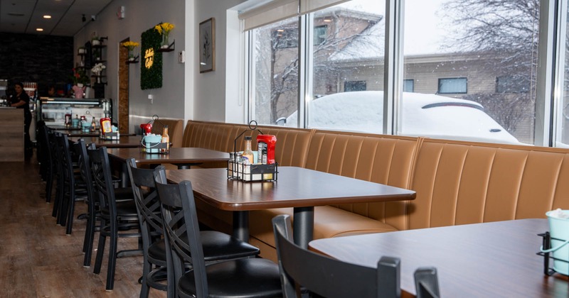 Interior, dining area, long banquette bench with tables and chairs, ready for guests