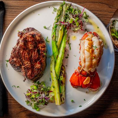 Grilled steak and lobster tail with asparagus and microgreens.
