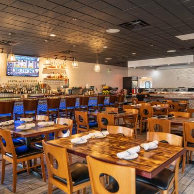 Modern interior with wooden tables, tiled bar, and warm hanging lights.
