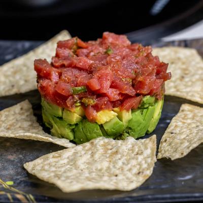 Tuna Tartar featuring diced tuna stacked on top of avocado and served with wonton chips.