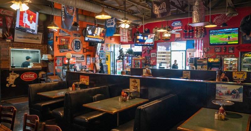 Interior, restaurant booths, hanging TV sets, a miscellany of decorations on walls