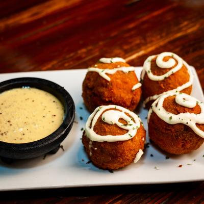 Fried brisket mac and cheese balls drizzled with creamy sauce, served with Alabama white BBQ sauce.