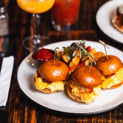 Breakfast sliders stacked with scrambled eggs, bacon, and melted cheese on brioche buns.