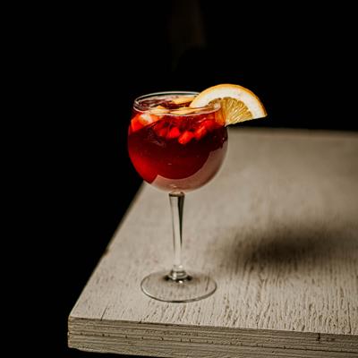 Red cocktail drink, garnished with lemon.