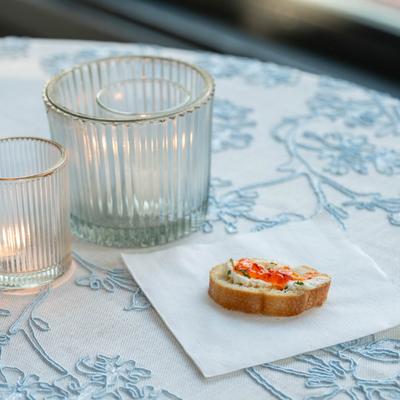 Crostini appetizer placed on a napkin on a table with candle holders.