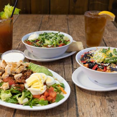 Three different salads on table with cocktails on the side