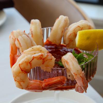 Shrimp cocktail featuring shrimp arranged in a clear glass with a red cocktail sauce.