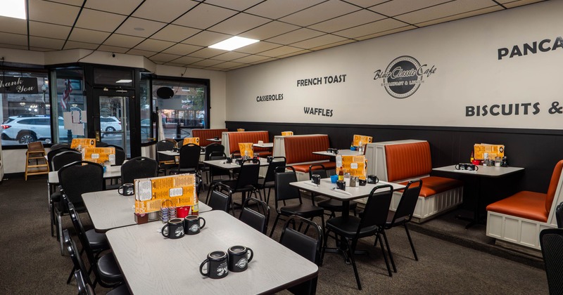 Interior of a diner-style restaurant with tables, chairs and orange booths.