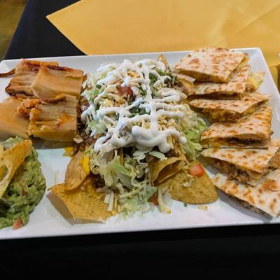 A platter with nachos, tamales and quesadillas.