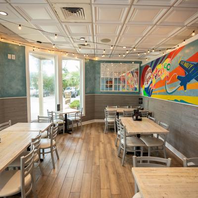 Interior featuring a colorful mural, tables, and string lights.