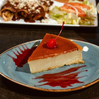 Flan topped with a layer of caramel sauce and garnished with a cherry.