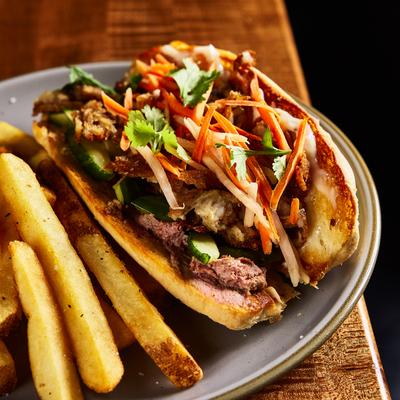 Bahn Mi topped with pickled carrots, daikon, and fresh cilantro, served with fries.
