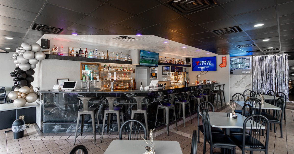 Interior, tables and chairs with bar and stools in the back