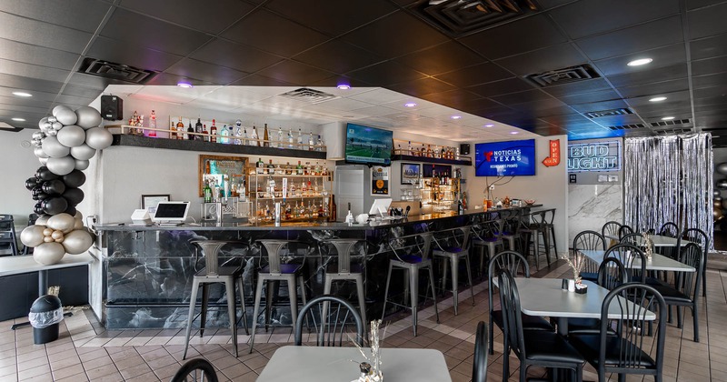 Interior, tables and chairs with bar and stools in the back