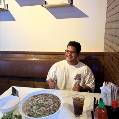 Customer holding two thumbs up, posing with a big bowl of soup.